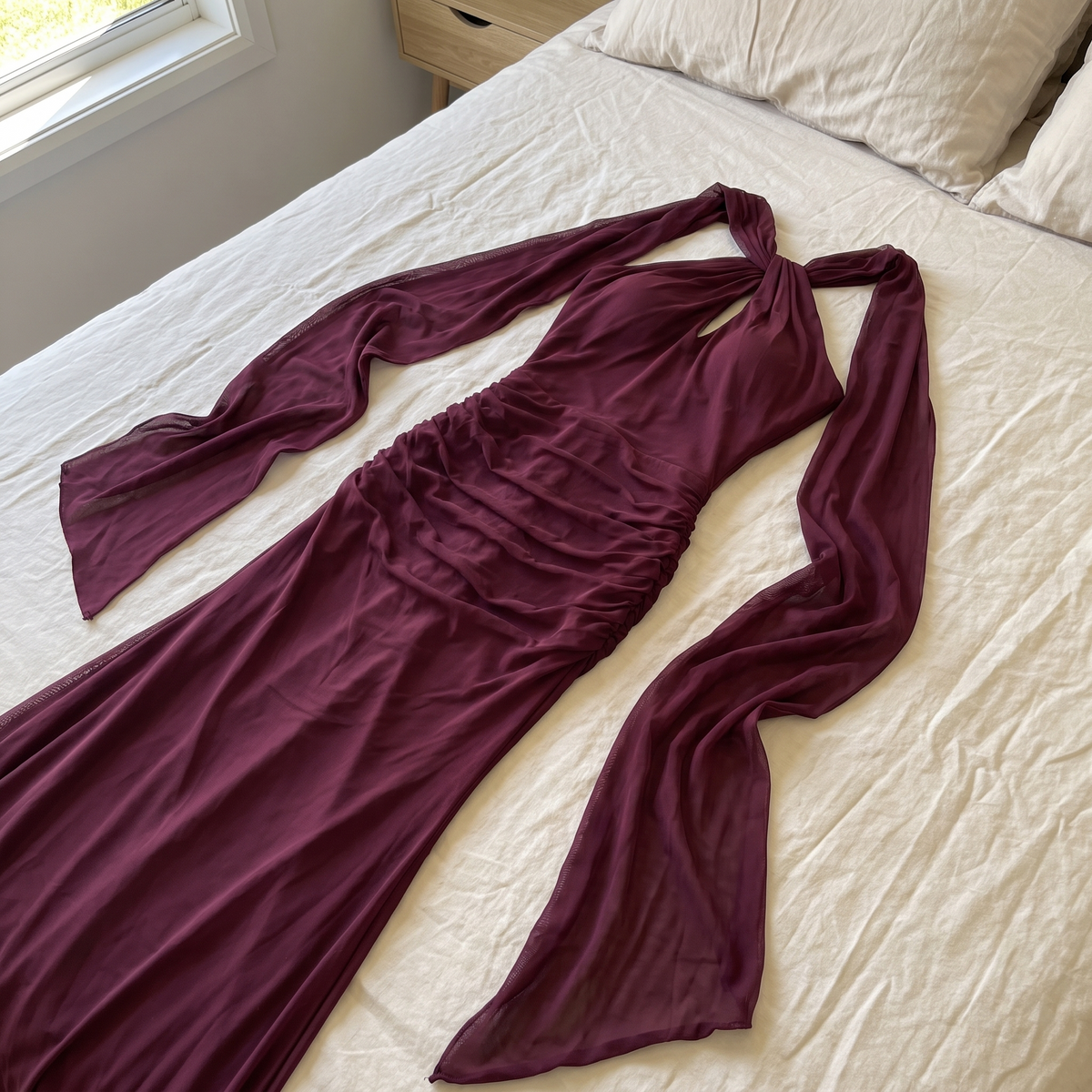 Burgundy Amara dress laid on cream bedding